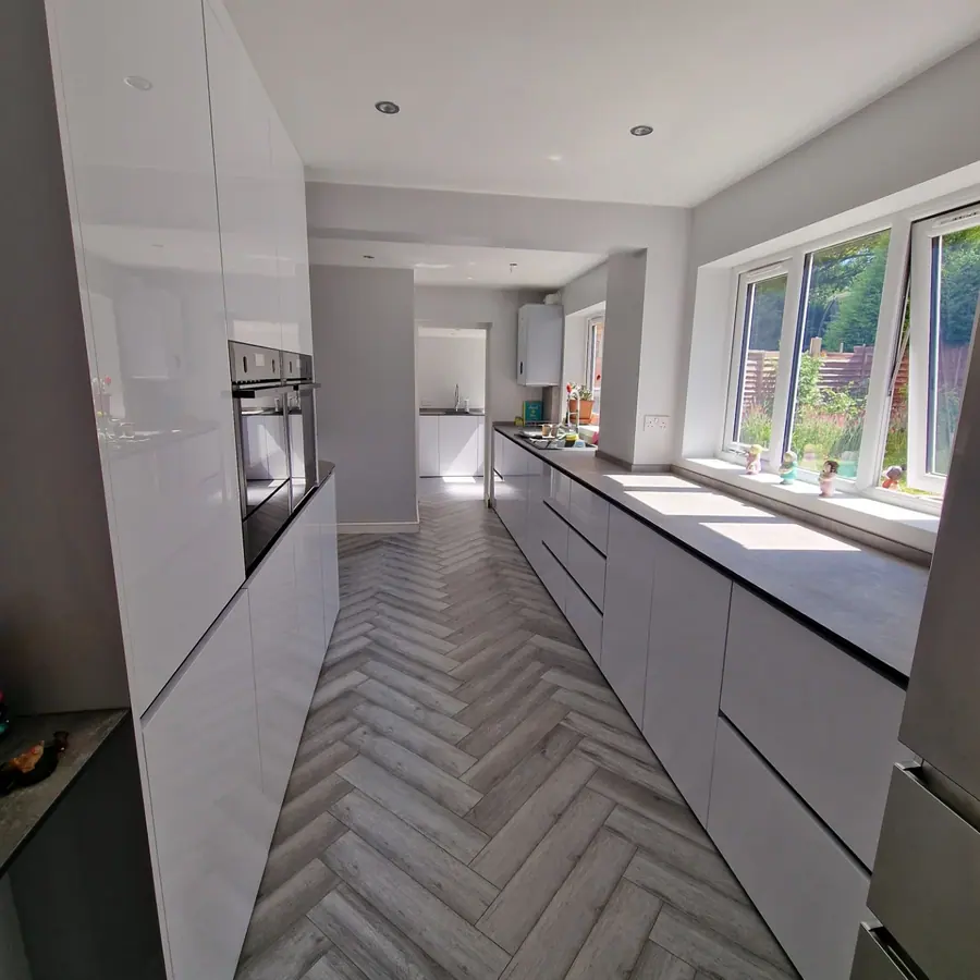 White gloss handleless kitchen with a herringbone floor